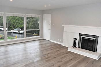 a living room with a fireplace and a large window at Trailhead Apartments at Tam Junction, Mill Valley, CA